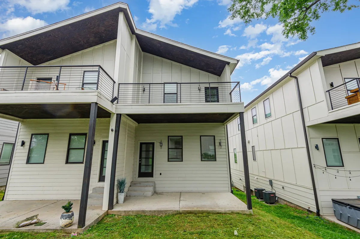 A contemporary two-story home with a welcoming balcony, manicured green lawn, and modern architectural lines. The property’s exterior is spacious, with ample room for outdoor gatherings and relaxation. The image conveys a sense of neighborhood proximity, suggesting multiple homes side by side.