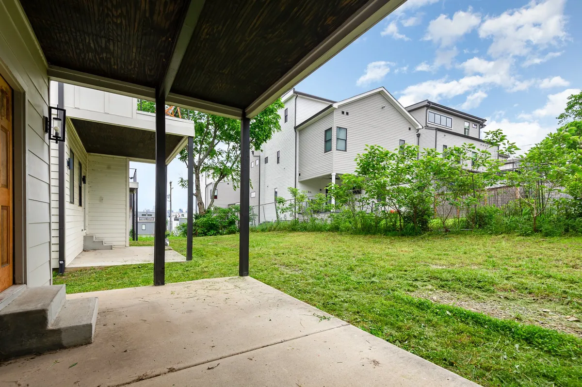 This exterior image showcases a lush green lawn surrounded by multiple houses, with a welcoming porch area that hints at shared outdoor spaces perfect for gatherings. The open yard and visible porches evoke opportunities for group activities, fresh air, and easy connectivity between the homes.