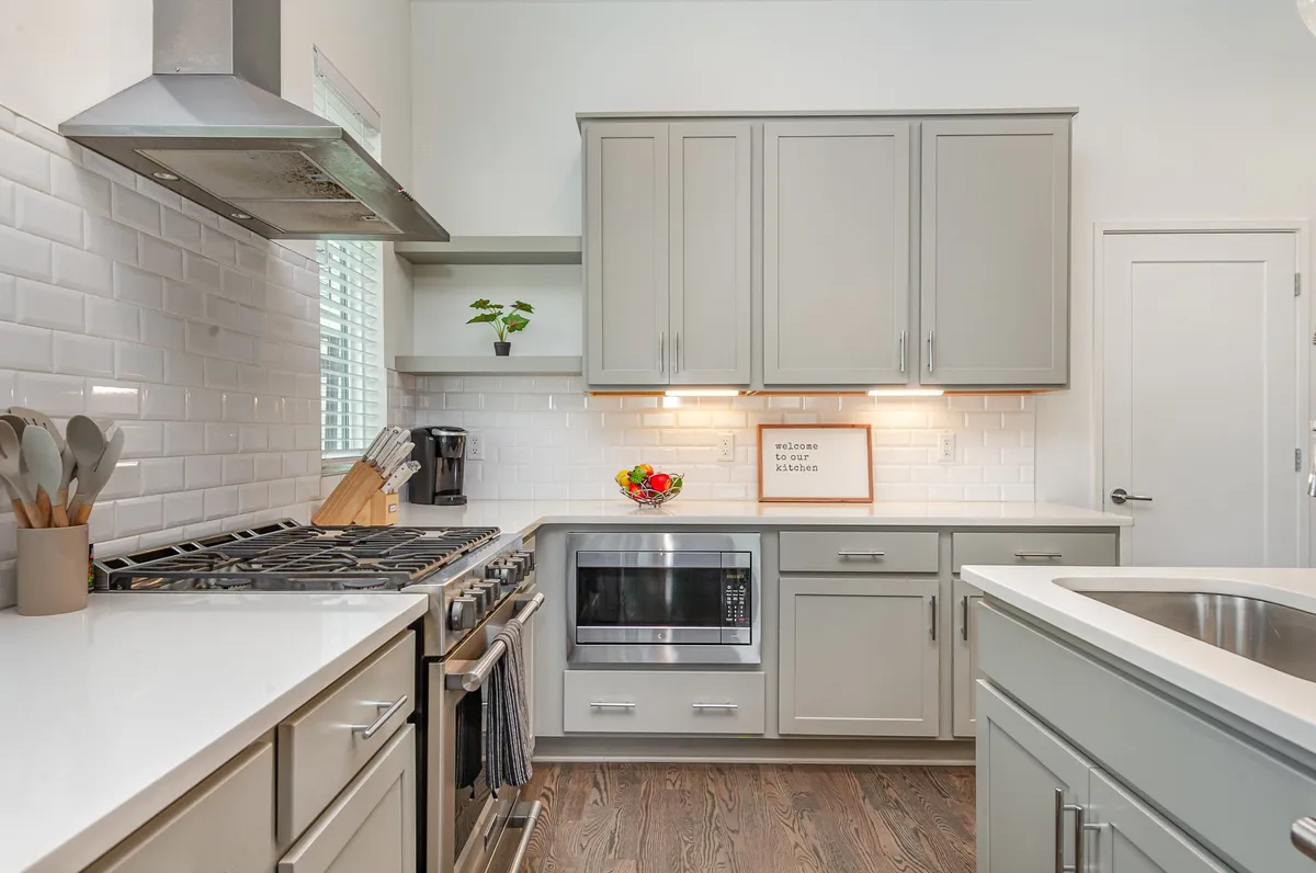 A friendly kitchen with a central island, stainless steel appliances, a colorful fruit bowl, and a playful 'welcome' sign. The setup invites cooking, gathering, and sharing stories over meals.